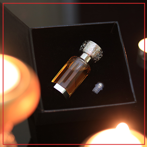 A bottle of perfume in a box with candles.